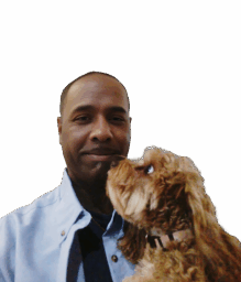 DeAngelo holding a small brown dog that is licking his cheek